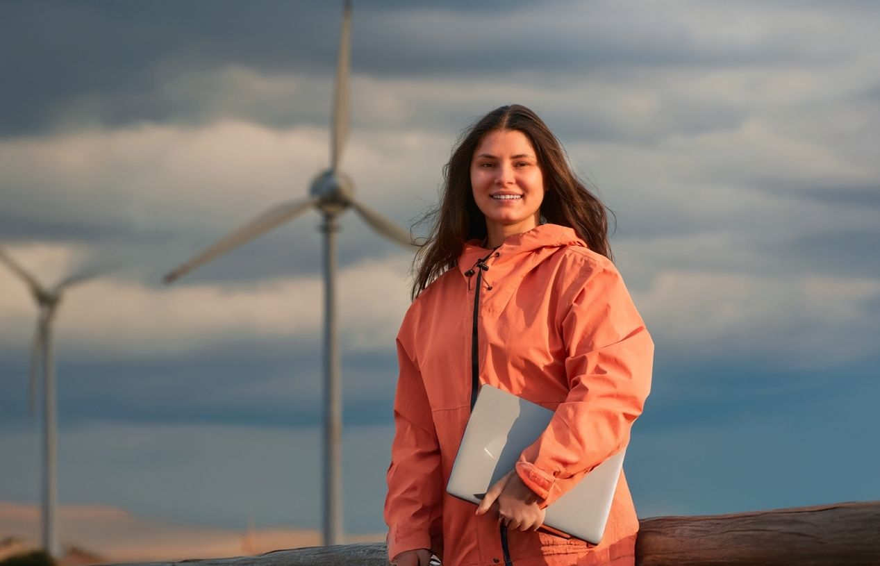 Étudiante en énergie renouvelable devant des éoliennes illustrant la transition énergétique
